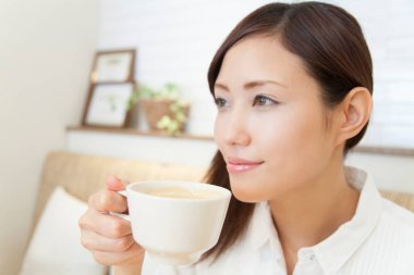 Kadın evde kahve fincanı içiyor. 