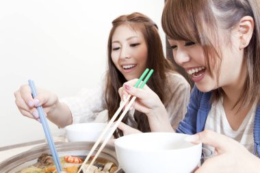 İki kadın birlikte yemek yiyor.