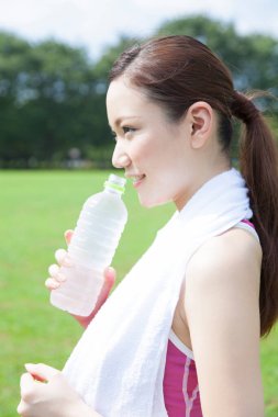 Parkta su içen güzel Asyalı kız.