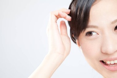 Asyalı kadın gülümsüyor ve saçlarına dokunuyor.