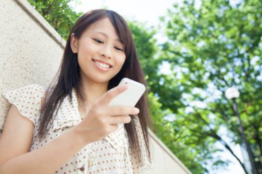 Sokakta akıllı telefon kullanan güzel Japon kadın.