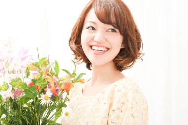 Bir buket taze çiçekle gülümseyen genç Japon kadın.