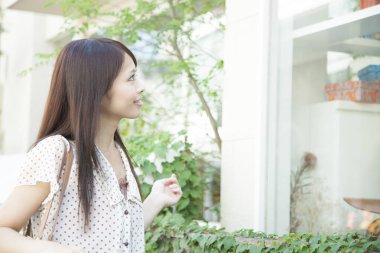 Kafenin camına bakan genç Asyalı kadın.