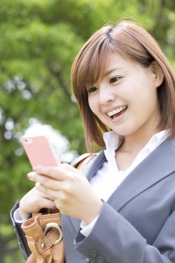 Parkta cep telefonu kullanan genç bir kadın. 