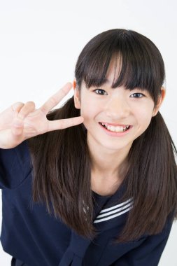 Beyaz stüdyo arka planında duran üniformalı Japon okul kızının portresi. 