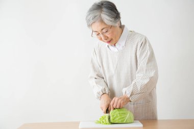 Yaşlı kadın sebze salatası hazırlıyor lahana doğruyor. 
