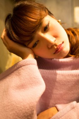 Masada oturan, süveterli, üzgün kadın.