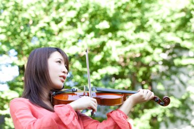 Kemanı olan genç Asyalı kadın.