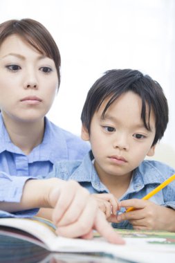 Genç Japon kadın oğluyla ev ödevi yapıyor.