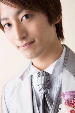 Genç Asyalı damat stüdyoda poz veriyor.