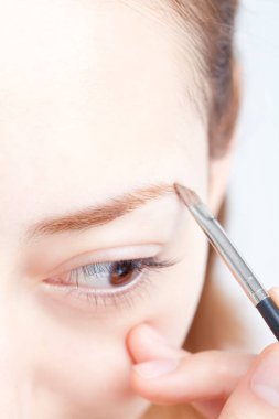 Kadın fırçayla kaş pudrası sürüyor. 