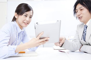 Genç işadamı ve işkadını ofiste tabletle birlikte çalışıyorlar. 