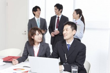 Dizüstü bilgisayarla çalışan bir grup genç Japon iş adamı.