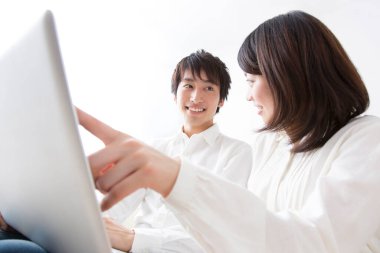 Bir adam ve bir kadın kanepede oturup laptopa bakıyorlar.