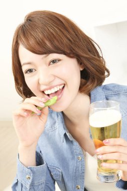 Neşeli Japon kadın evde bira içiyor.