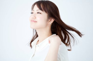 Beyaz gömlekli genç Asyalı kadın stüdyoda poz veriyor. 