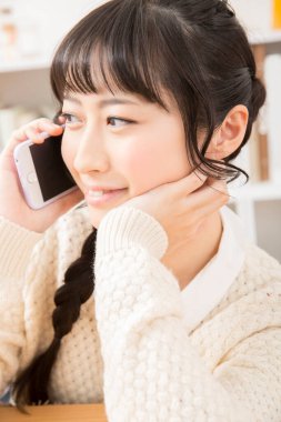 Güzel Asyalı genç bir kadın telefonda konuşuyor.