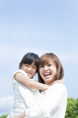 Asyalı anne ve kızı parkta oynuyorlar.