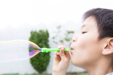 Çocuk parkta balon üflüyor.