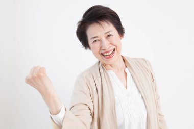 Beyaz arka planda üst düzey Japon kadını kutlayan mutlu bir portre.