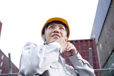 Miğferli Asyalı işçi başka tarafa bakıyor.