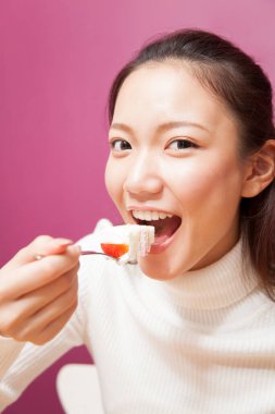 Asyalı kadın tatlı pasta yiyor.