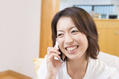 Oturma odasında cep telefonuyla konuşan genç bir kadın.