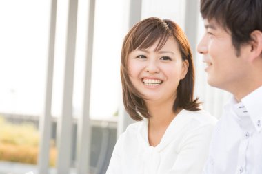 Genç bir kadınla gülümseyen Asyalı bir adam. 