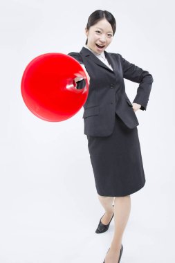 Beyaz arka planda izole edilmiş megafonla takım elbise giyen Asyalı genç bir iş kadını.. 