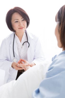 Asyalı kadın doktor bir hastayı muayene ediyor.