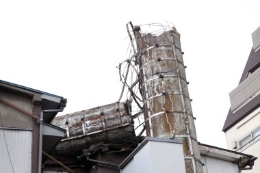 Hasarlı endüstriyel yapı bitişik kentsel binalara çöküyor