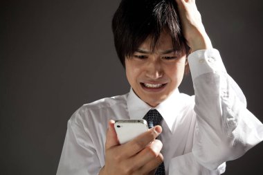 Cep telefonu olan stresli Asyalı genç bir adam.