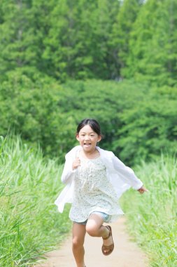 Tarlada koşan küçük tatlı bir Japon kız.