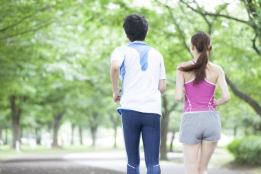 Genç çift güneşli bir günde parkta koşuyor.