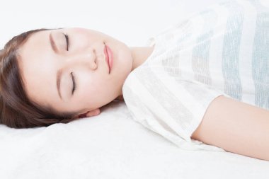 Beyaz yatakta uyuyan genç kadın.