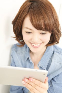 Dijital tablet kullanan gülümseyen Asyalı kadın