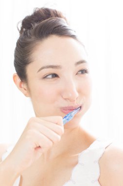 Dişlerini fırçalayan Asyalı kadın. 