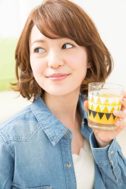 Güzel Asyalı kadın bir bardak meyve suyu tutuyor.