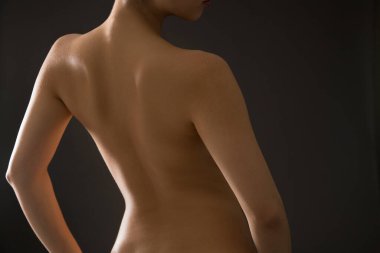 Stüdyoda poz veren genç ve çıplak bir kadın. 