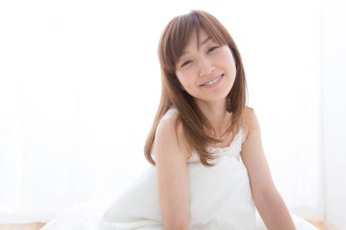 Genç kadın yatakta oturuyor.