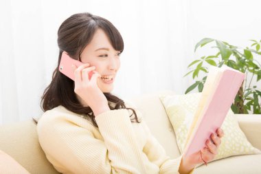 Akıllı telefondan konuşan gülümseyen Asyalı kadın. Toplantı programına bakıyorum. randevu alınıyor