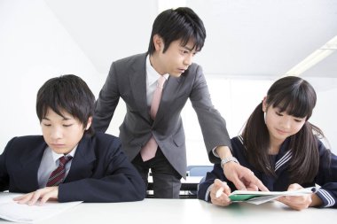 Asyalı erkek öğretmen derste öğrencilere materyali açıklıyor 