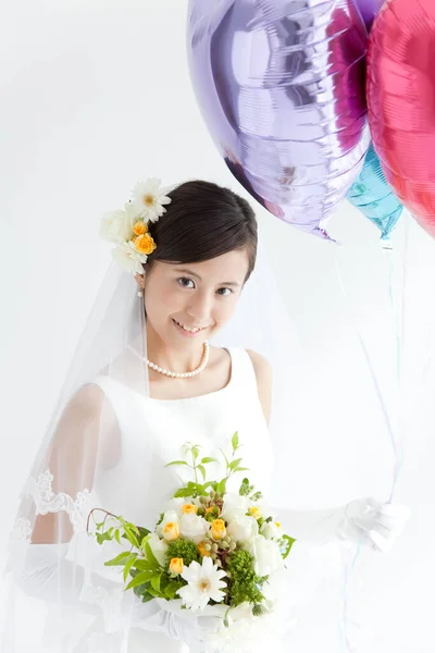 a bride holding a bouquet of flowers and balloons