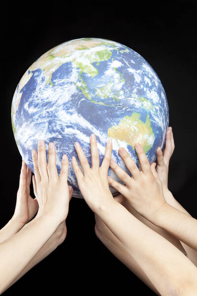the human hands holding a globe on black background