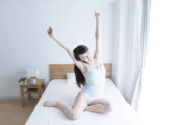 young woman stretching in bed at home
