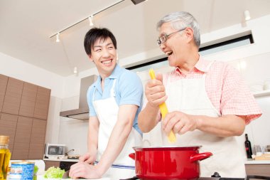Mutlu baba ve oğul ev mutfağında birlikte yemek pişiriyor.