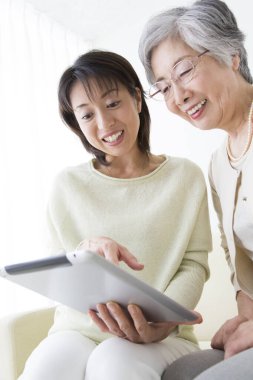 Mutlu Asyalı kadınlar evde dijital tablet kullanıyorlar. 