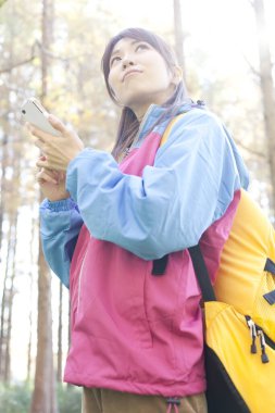 Ormanda cep telefonu kullanan bir kadın yürüyüşçü