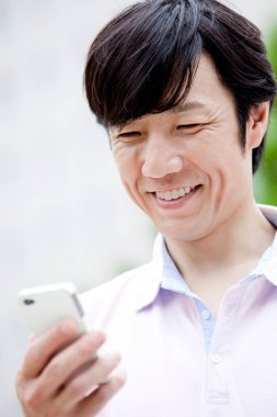 Mutlu Asyalı adam cep telefonu kullanıyor.