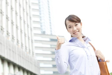 Şehirde başparmağıyla gülümseyen Asyalı kadın. 